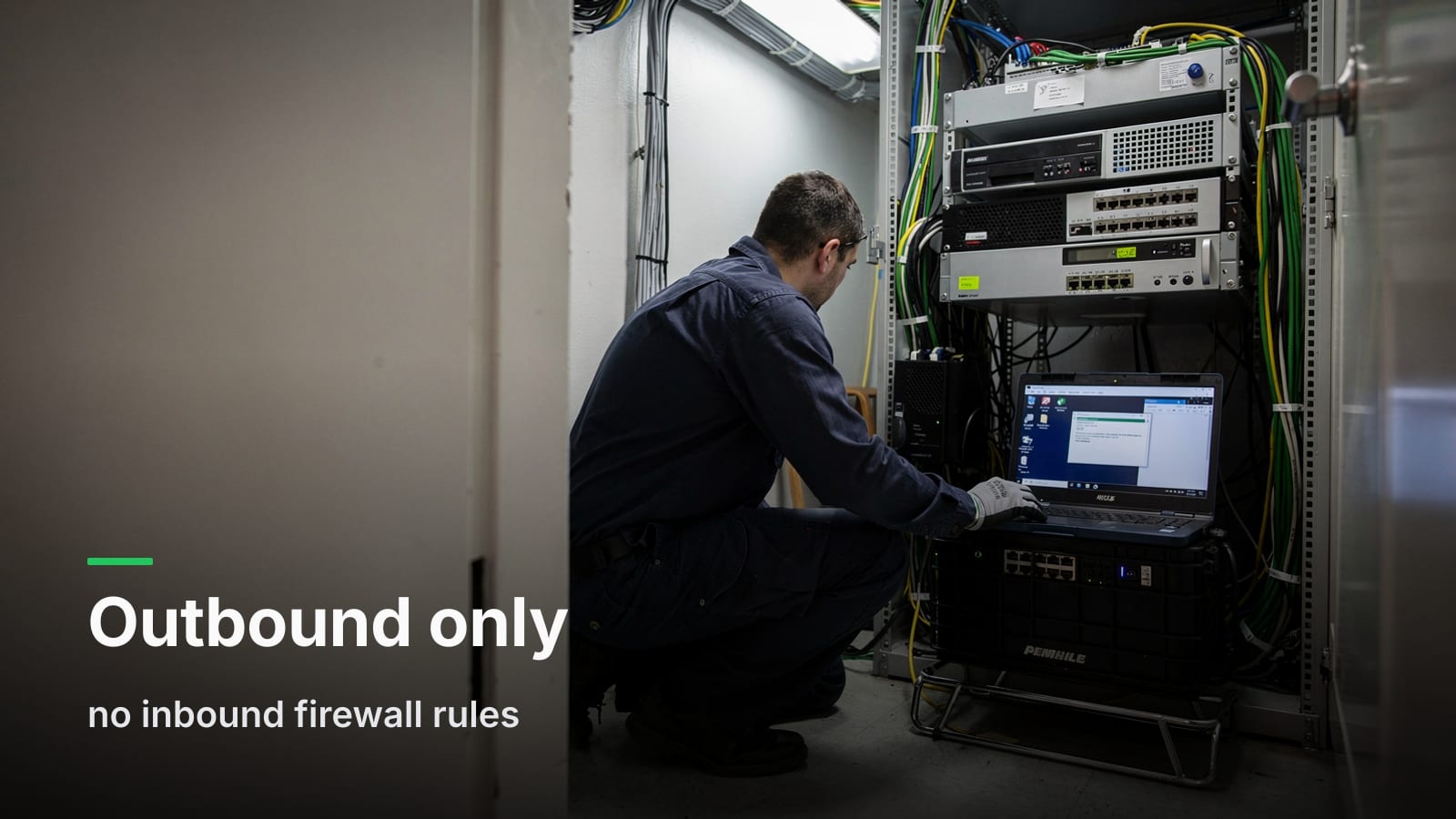 Technician kneeling at a server rack in a small closet, working on a Windows Server console screen.